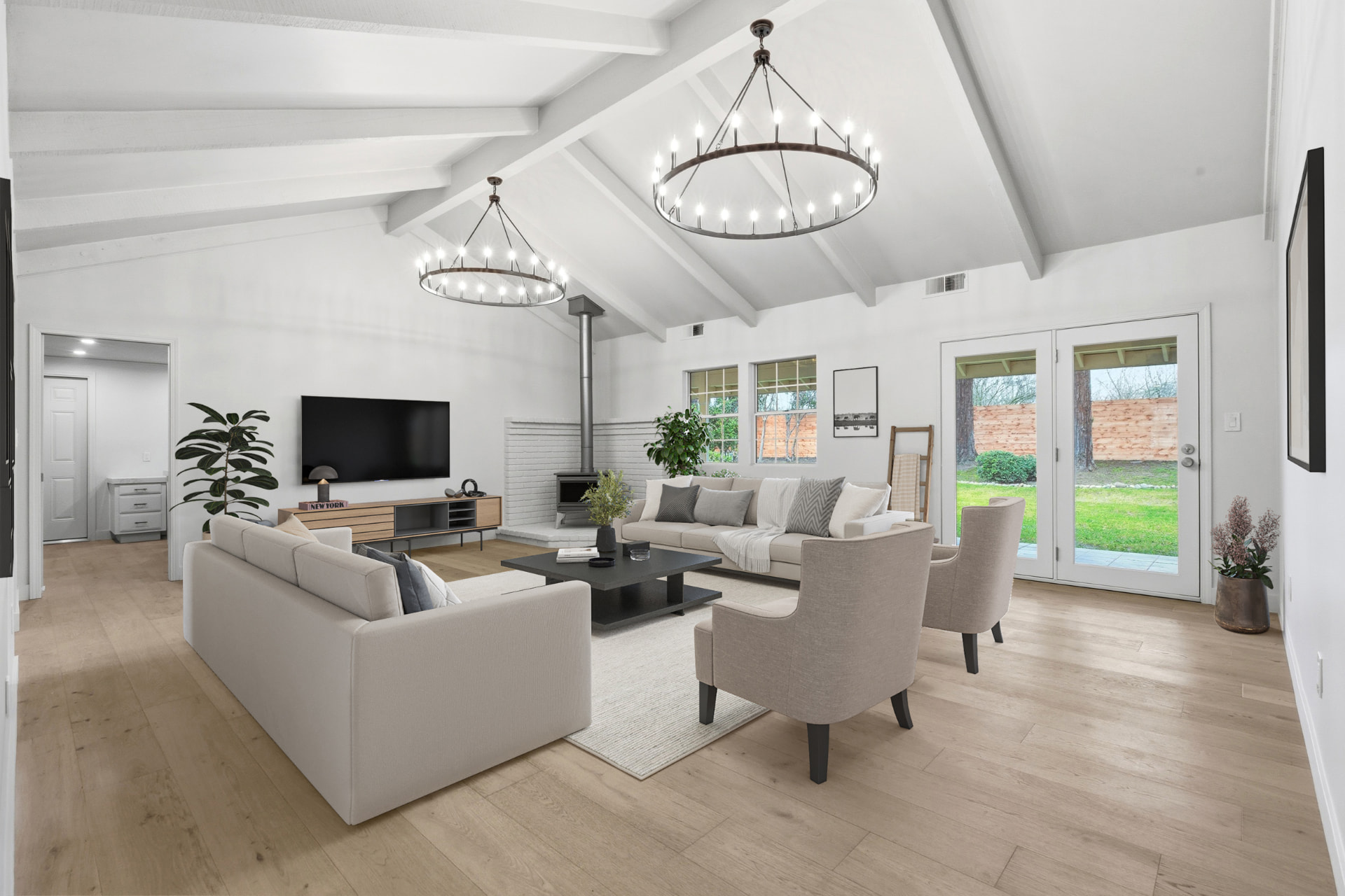 Vaulted living room with chandeliers, wood stove, and doors to the backyard