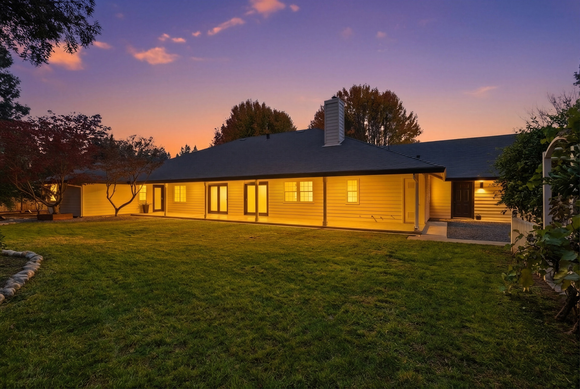 Expansive backyard lawn and covered patio at sunset