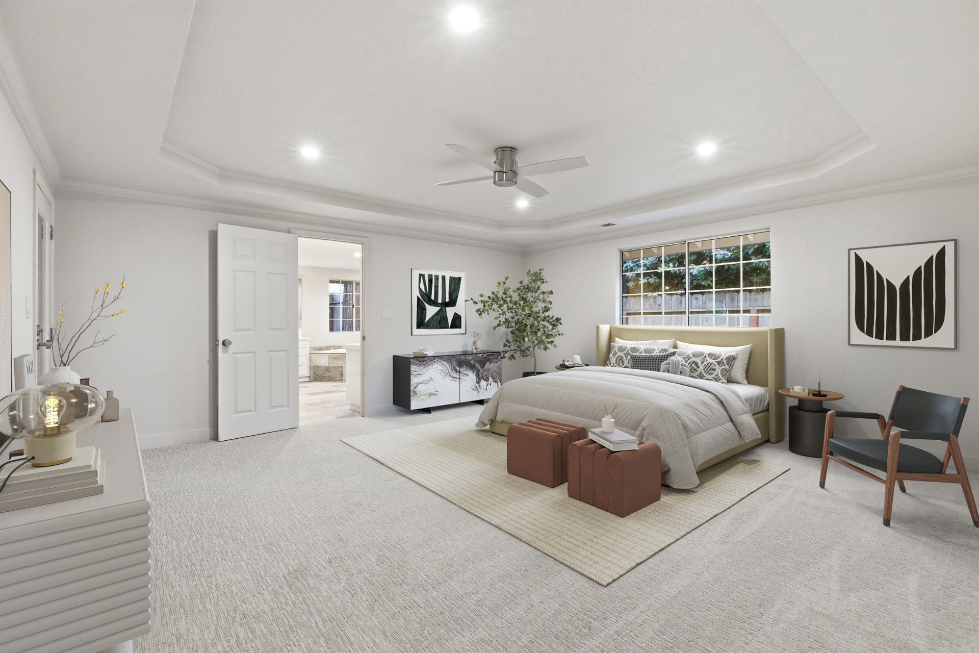 Spacious primary bedroom with tray ceiling and backyard view